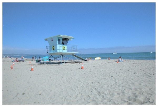 A lifeguard tower marked two stands on a beach beside the sea.